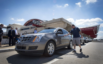 People standing next to parked Cadillac SRX  driverless car